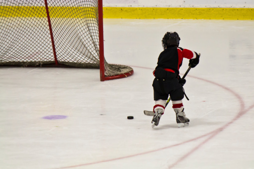 Child skating and playing hockey in an arena